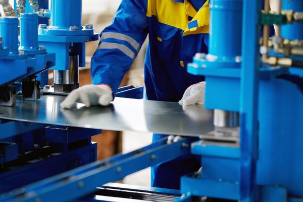 manufacturing employee cutting sheet metal on machine