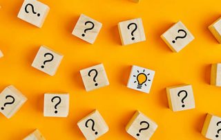 Concept of to find a creative idea or problem solving. Question mark and light bulb icons on wooden cubes on yellow background.