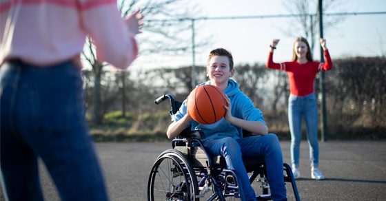 young person in a wheelchair playing basketball with friends